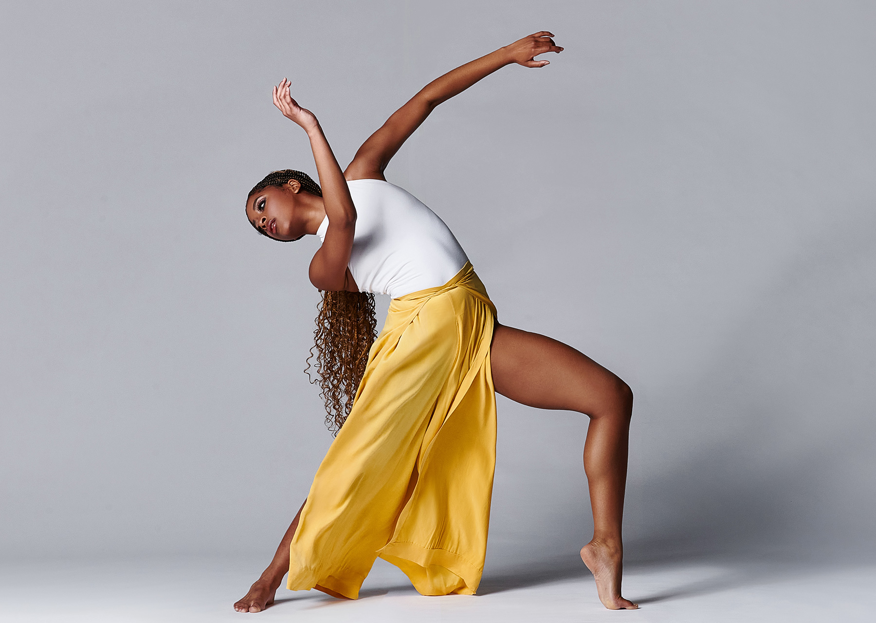 Mason School of Dance student in yellow and white in a pose against a gray background