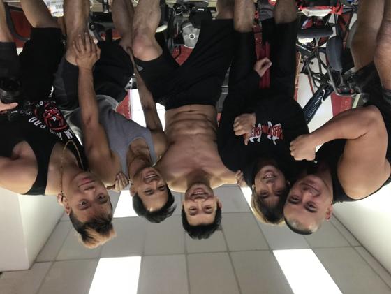 A group of men stand together in a martial arts gym after a training session. From left to right: Andy Le, Brian Le, Simu Liu, DY Sao, and Joseph Le. 