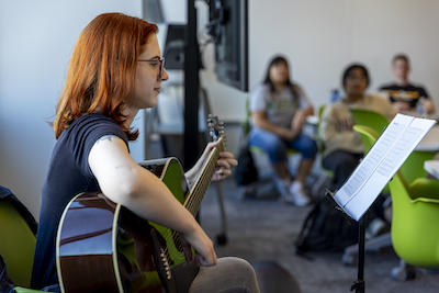 Music alumna and Mason staff member, Caitlyn Loweth Rivero playing guitar for the HNRS360 students. Photo by Cristian Torres/Office of University Branding.